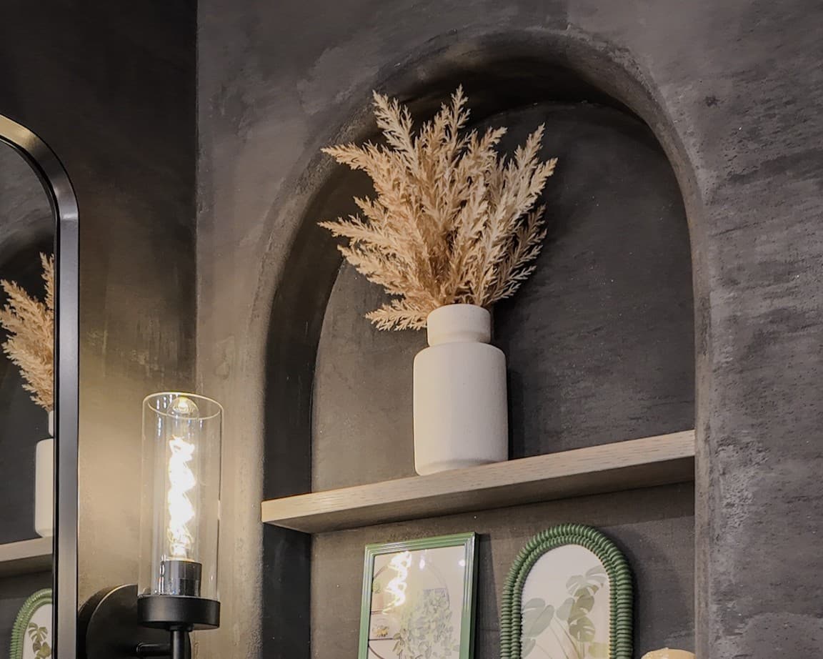 Elegant plaster wall finish with natural texture, wooden shelf with vase and pampas grass decor