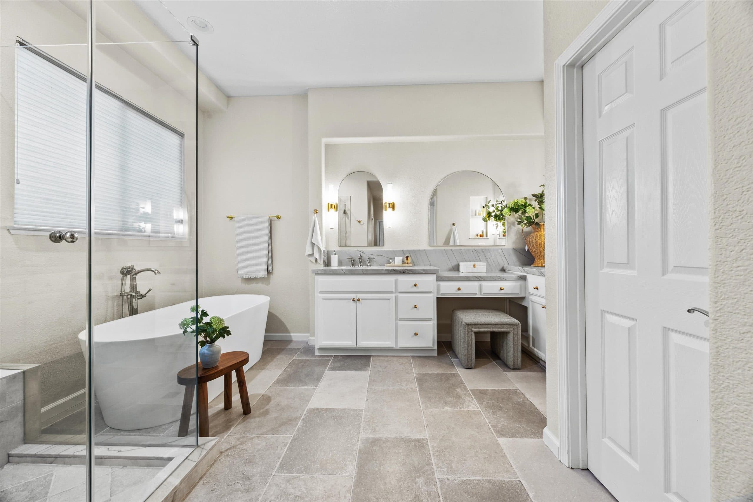 Wide-angle view of completed master bathroom showing vanity, makeup station, and tile floor