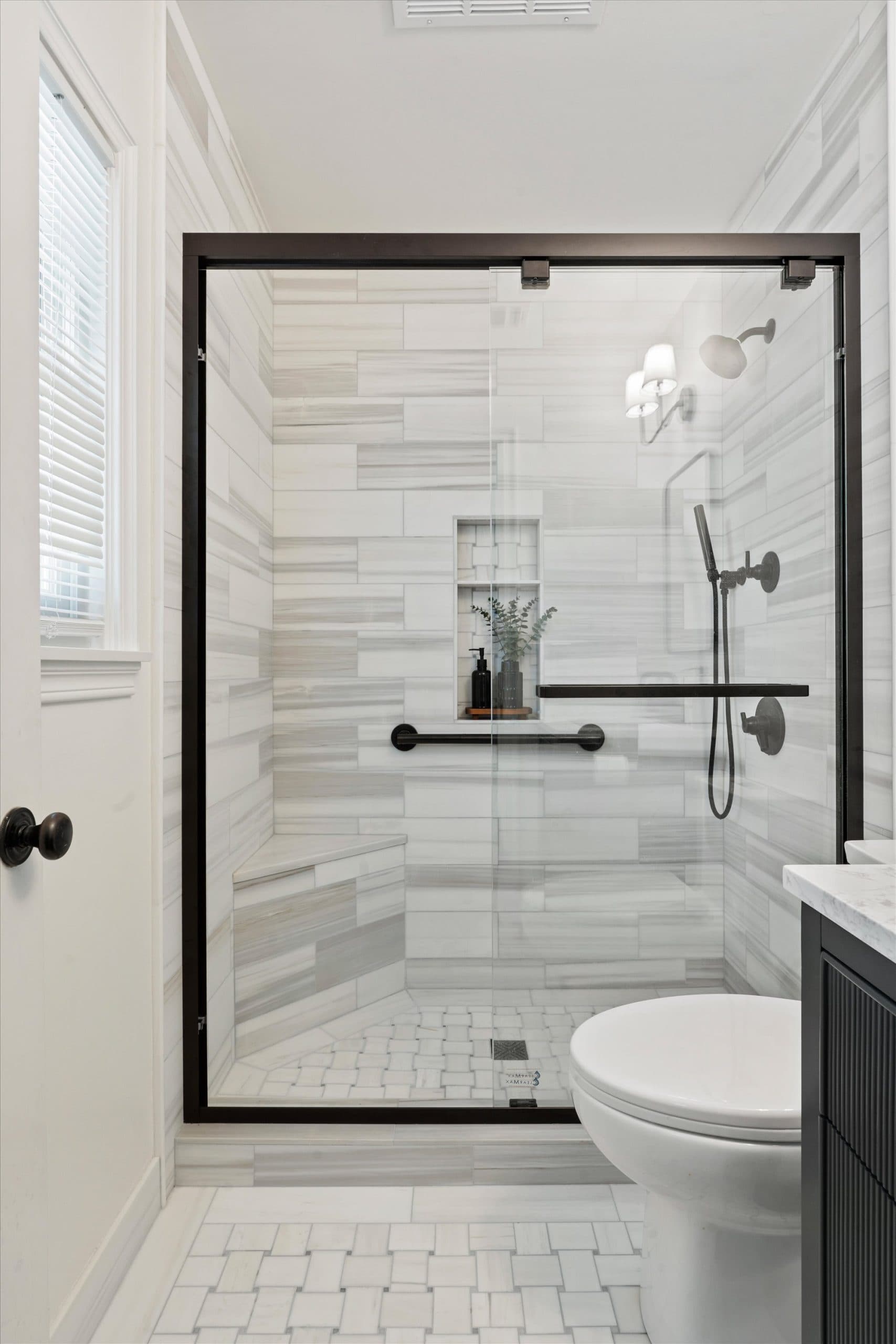 Walk-in shower with marble-look tile and black-framed glass Sacramento remodel